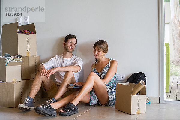 Junges Paar in neuem Haus  umgeben von Pappkartons