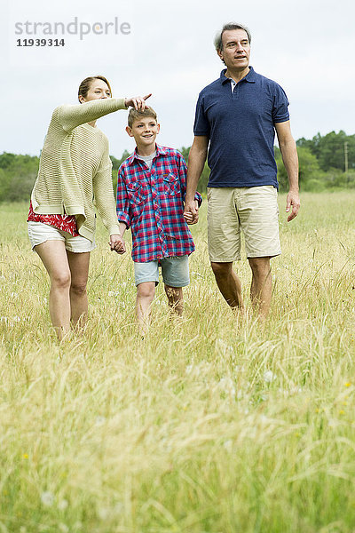 Familie mit einem Kind beim gemeinsamen Spaziergang auf freiem Feld