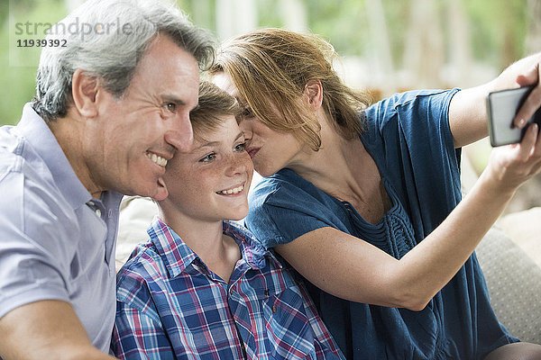 Eltern und junger Sohn posieren für einen Selfie