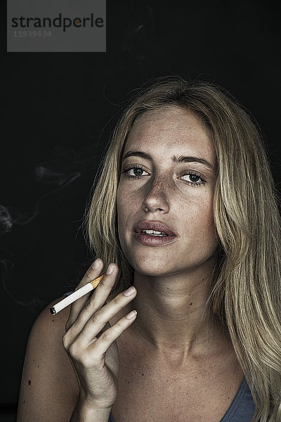 Junge Frau raucht Zigarette  Porträt