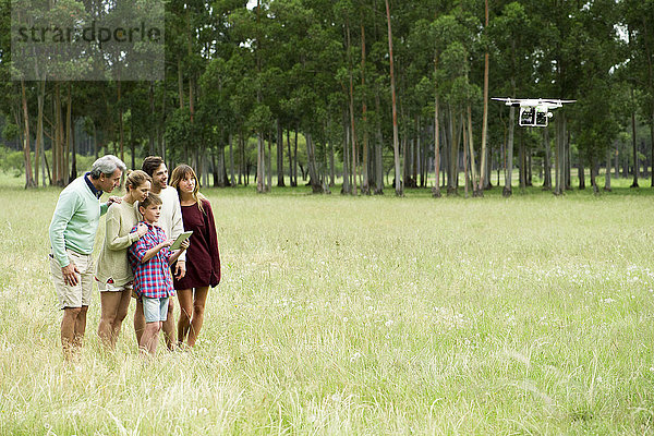 Junge bedient ferngesteuerte Drohne  während Eltern und Großeltern zusehen.