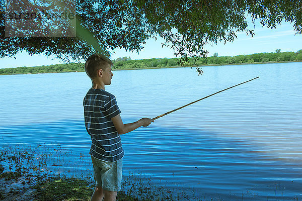 Junge fischen am Seeufer