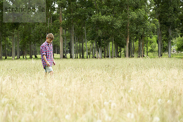 Junge geht allein durchs Feld