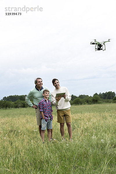 Mehrgenerationen-Familie spielt mit Drohne im Feld