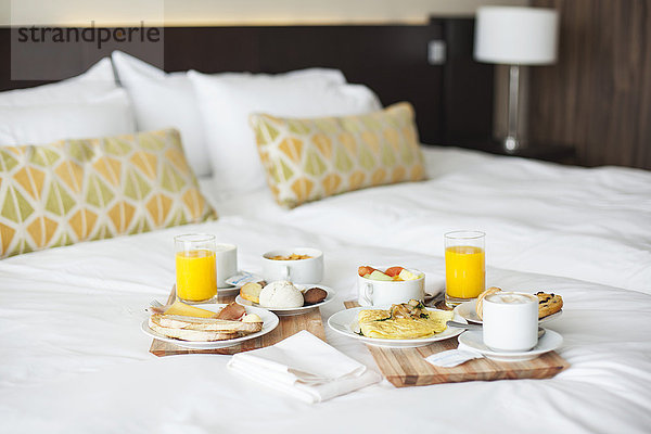 Frühstückstabletts auf dem Bett im luxuriösen Hotelzimmer