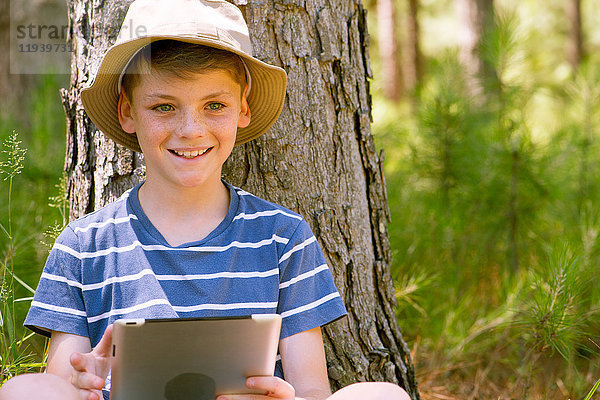 Junge mit digitalem Tablett im Wald