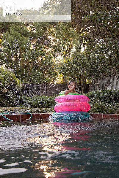 Junges Mädchen  das inmitten von aufblasbaren Ringen im Freibad steht