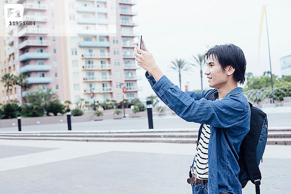 Junger Mann im Freien  fotografiert mit Smartphone