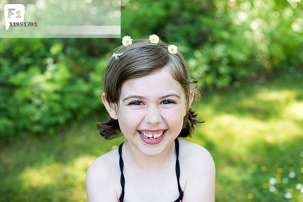 Porträt eines jungen Mädchens im Freien  mit Gänseblümchen im Haar  lächelnd