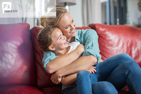 Mutter und Tochter auf dem Sofa kuscheln und lächeln