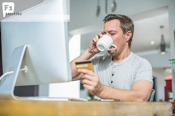 Mann im Besitz einer Kreditkarte mit Computer