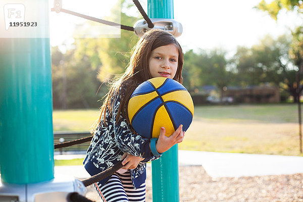 Mädchen hält Basketball auf dem Spielplatz