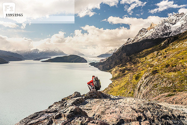 Männlicher Wanderer kauert  um den Grey-See und Gletscher zu überblicken  Torres del Paine Nationalpark  Chile