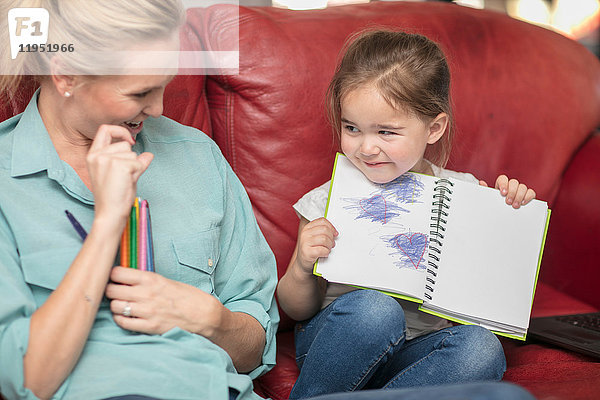 Tochter zeigt stolz Bleistiftzeichnungen der Mutter
