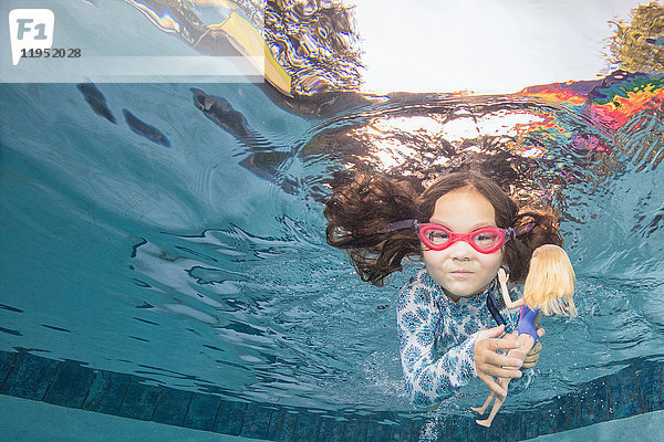 Unterwasser-Porträt eines schwimmenden Mädchens  das eine Puppe hält