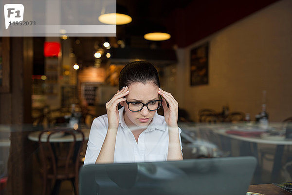 Frau im Café mit gestresstem Laptop