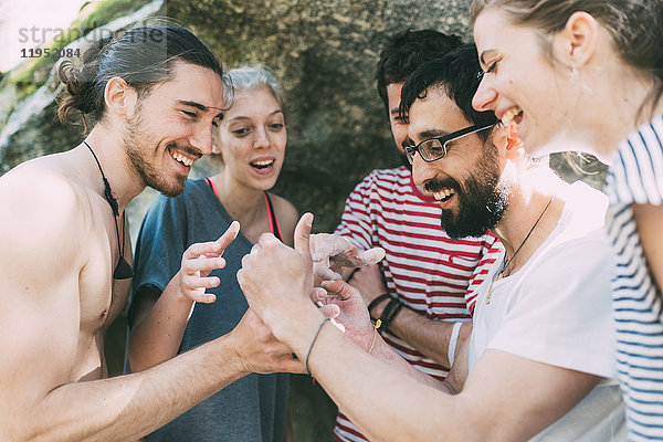 Fünf erwachsene Boulderfreunde schauen und lachen über Smartphone  Lombardei  Italien