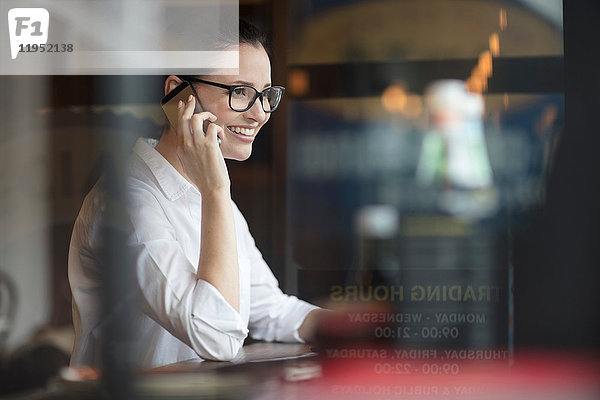 Frau im Café mit Smartphone lächelt