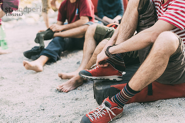 Nackenansicht von erwachsenen Boulderfreunden  die sich Socken anziehen und Turnschuhe tragen  Lombardei  Italien