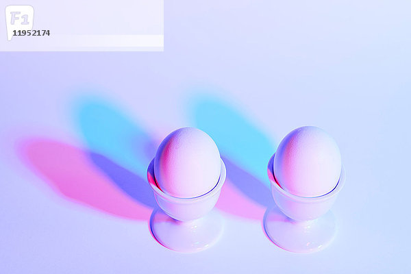 Zwei Eier in Eierbechern auf violettem Hintergrund