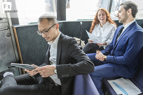 Geschäftsmann betrachtet digitales Tablet auf Passagierfähre