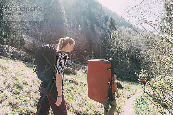 Erwachsene Freunde mit Bouldermatten-Rucksack wandern auf ländlichem Weg  Lombardei  Italien