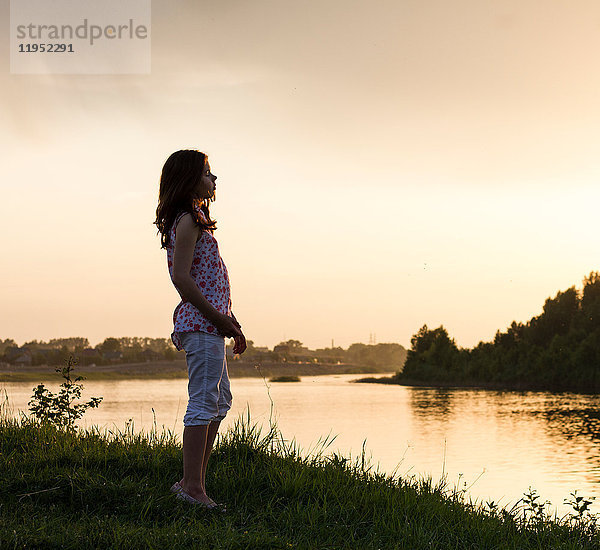 Teenager-Mädchen schaut bei Sonnenuntergang über den Fluss