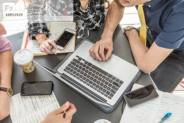 Ausschnitt eines Geschäftsteams mit Laptop bei einem Café-Meeting