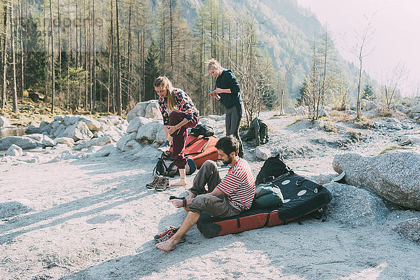 Erwachsene Boulderfreunde ziehen am Flussufer ihre Trainer aus  Lombardei  Italien