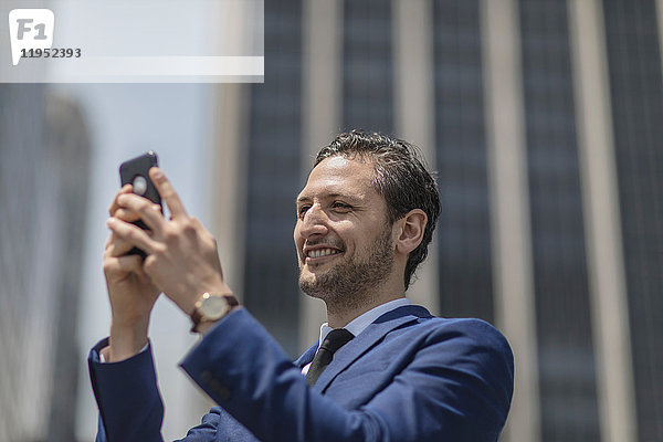 Lächelnder junger Geschäftsmann beim Selbstausstieg vor einem Bürogebäude  New York  USA
