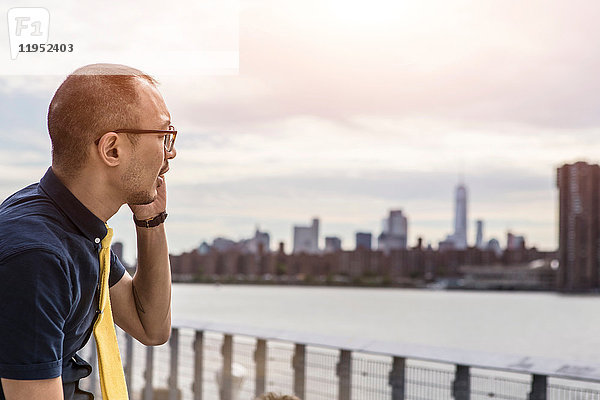 Geschäftsmann am Wasser beim Telefonieren mit Smartphones  New York  USA