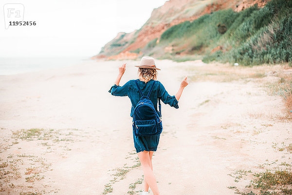 Mittlere erwachsene Frau tanzt am Strand entlang  Rückansicht