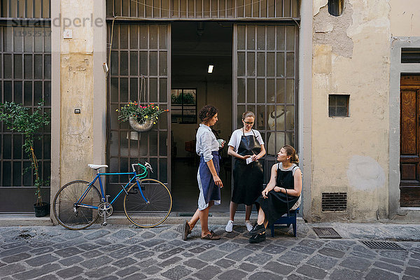 Drei Juwelierinnen machen eine Kaffee- und Zigarettenpause vor dem Eingang der Schmuckwerkstatt