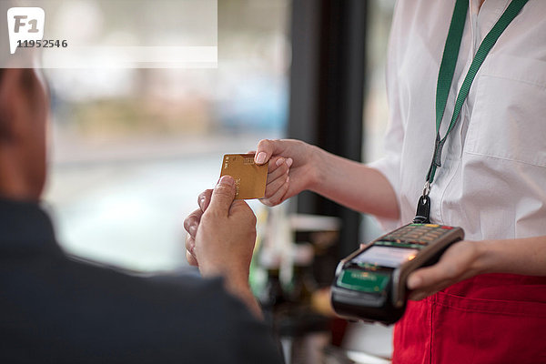 Kunde gibt Kreditkarte an Kellnerin zur Zahlung am Kartenautomaten ab