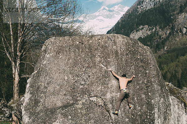 Rückansicht eines jungen männlichen Boulderers beim Bouldern  Lombardei  Italien