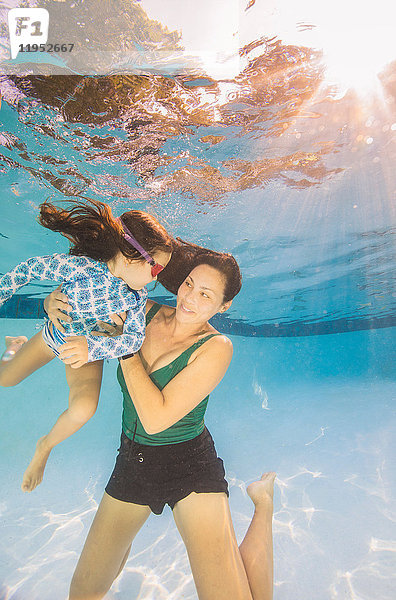 Unterwasseransicht einer reifen Frau  die schwimmend ihre Tochter hält