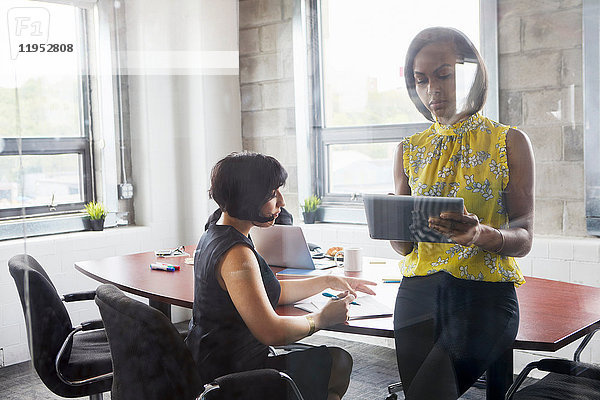 Zwei Frauen arbeiten zusammen im Besprechungsraum  Brainstorming  Verwendung eines digitalen Tablets