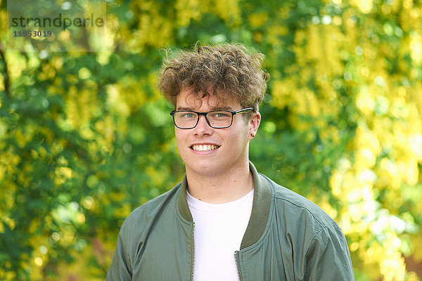 Porträt eines jungen Mannes mit lockigem Haar  der lächelnd in die Kamera schaut