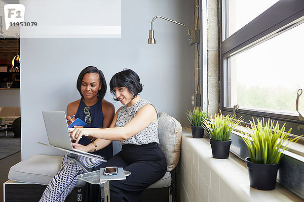 Zwei Frauen sitzen  am Laptop arbeiten  am Laptop-Ständer