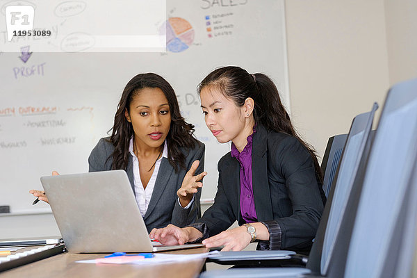 Zwei Geschäftsfrauen im Büro mit Blick auf den Laptop-Bildschirm