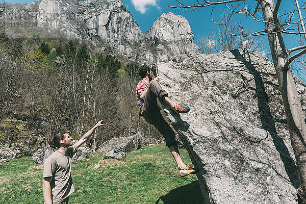 Junge männliche Boulderer zeigen auf Frauen beim Bouldern  Lombardei  Italien