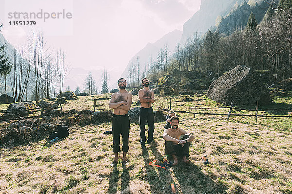 Vier erwachsene Freunde beobachten männliches Bouldern vom Tal aus  Lombardei  Italien