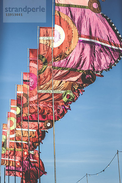 Tiefblick auf eine Reihe von rosa und orangefarbenen Bannern  Flaggen  die bei einem Sommer-Musikfestival in der Brise flattern.