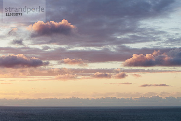 Blick vom Land über den Ozean bis zum Horizont. Sonnenuntergangslicht  das auf die Wolken scheint.