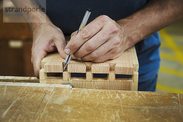 Nahaufnahme einer Person  die in der Werkstatt eines Bootsbauers arbeitet und zwei Holzstücke zusammenfügt.
