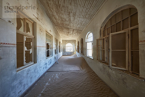 Blick auf einen Korridor in einem heruntergekommenen Gebäude voller Sand.