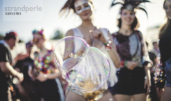 Schwelgt bei einem Sommer-Musikfestival große Seifenblasen im Vordergrund.