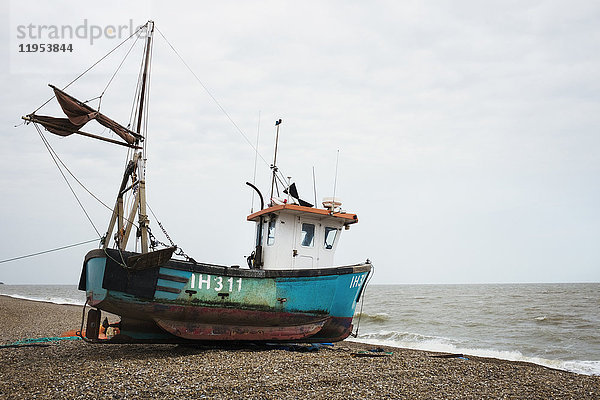 Blaues Fischerboot  das auf einem Kiesstrand nahe dem Wasser liegt  Aldeburgh  Suffolk  England.