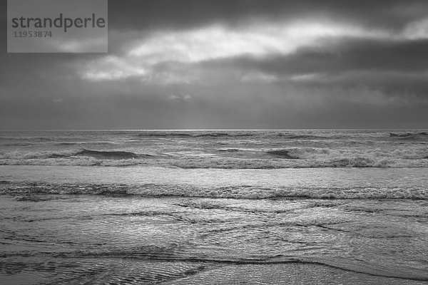 Blick vom Strand aufs Meer an einem bedeckten Tag und in der einsetzenden Dämmerung.