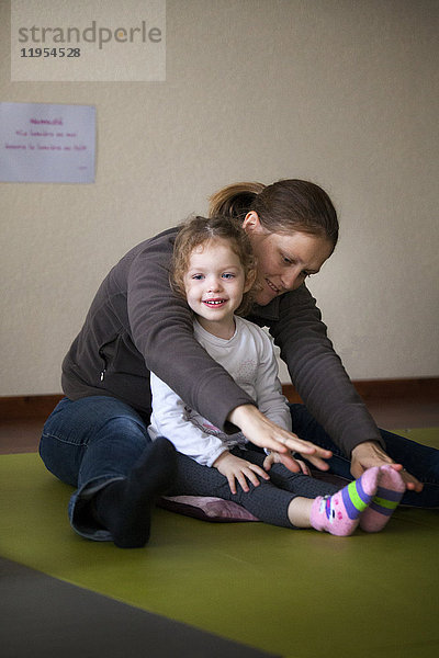 Reportage über eine Eltern-Baby-Yoga-Sitzung. Während der Sitzung demonstriert die Lehrerin verschiedene Übungen  die leicht zu Hause nachgemacht werden können. Diese Übungen ermöglichen es den Teilnehmern  innezuhalten  sich zu entspannen und diesen Moment mit ihrem Baby zu teilen.